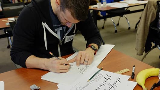 Person writing notes during a workshop session at a wooden table