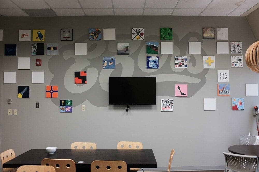 Element Three team members working at office wall with achievement banners