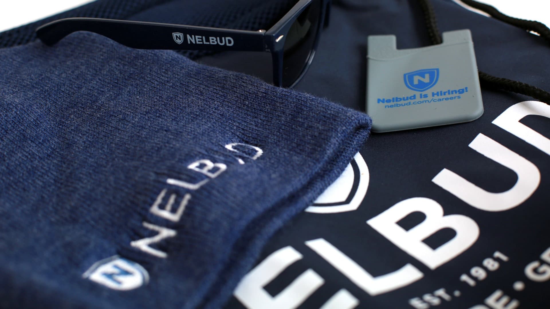 Nelbud branded merchandise showing logo on t-shirt and hiring advertisement