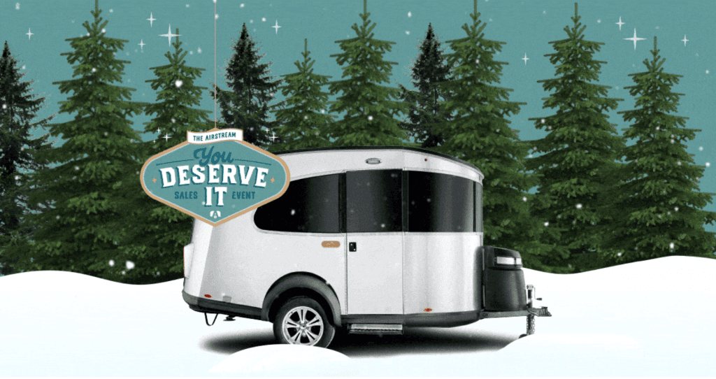 Airstream travel trailer in a snowy forest with The Airstream You Deserve It Sales Event badge