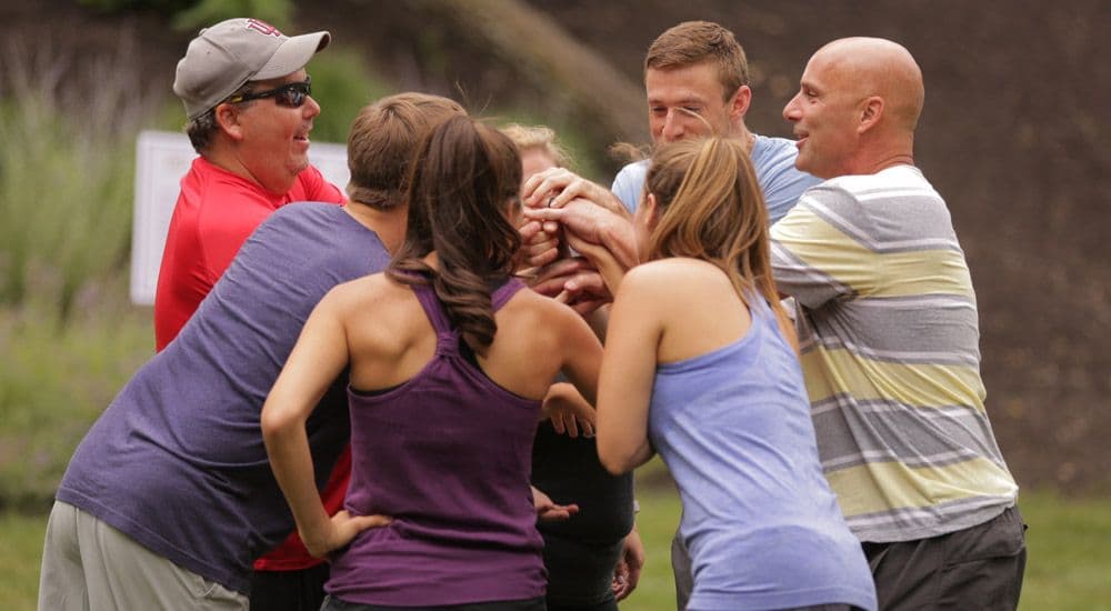 Team of people participating in company team-building activity outdoors