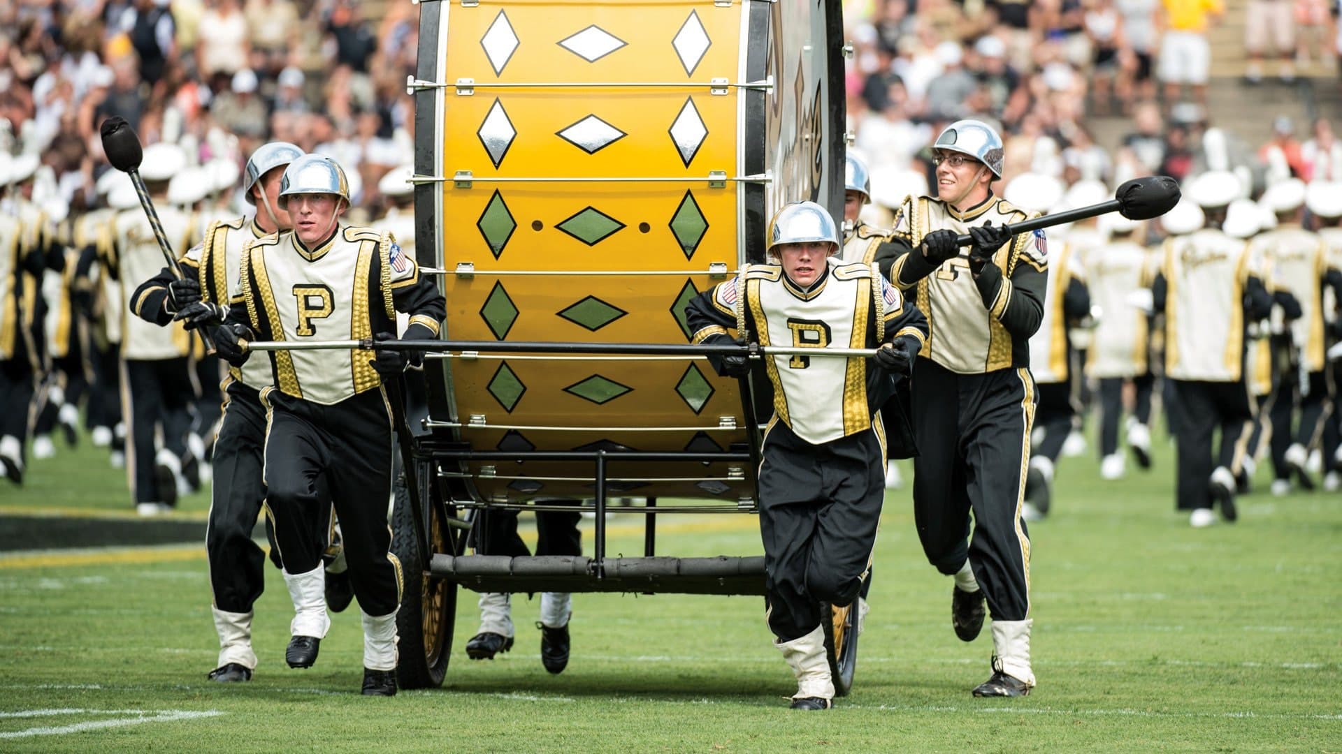 Football marching band members in white and gold uniforms pulling decorated wagon