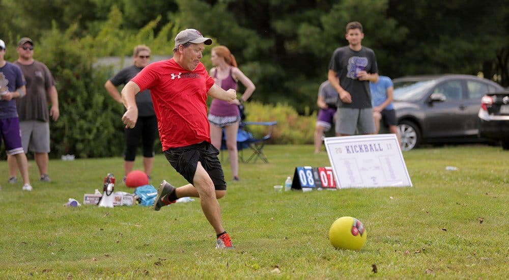Outdoor game event with people playing kickball in summer