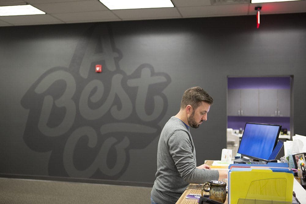 Man working at desk in office space with Best logo on wall