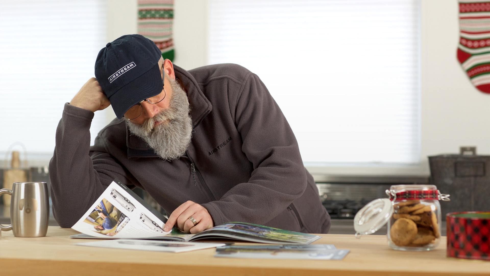 Man in Airstream cap reading with festive stockings hanging in background