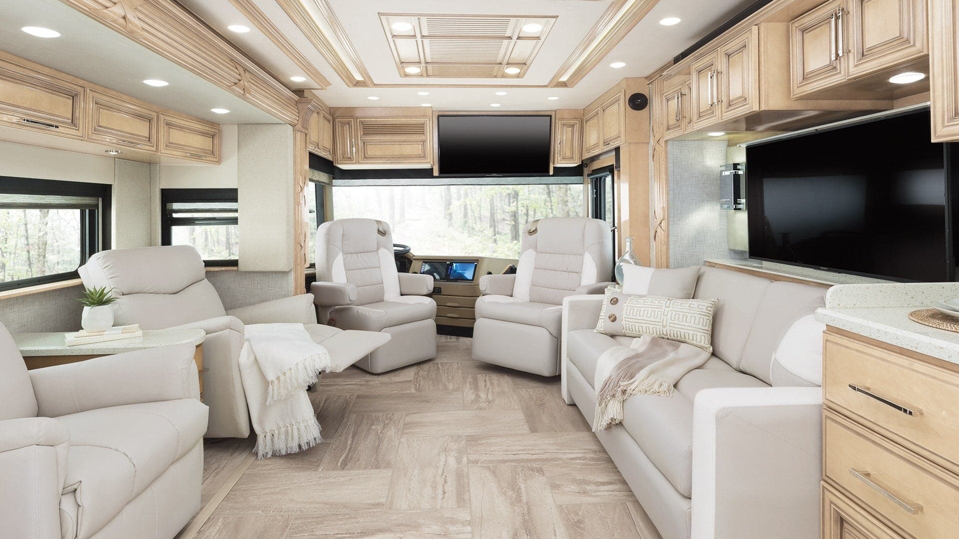 Luxury motorhome interior with cream furniture, wood cabinetry, modern entertainment center