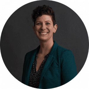 Woman with short dark hair wearing teal blazer against blurred background professional headshot