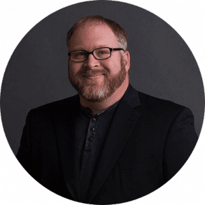 Man with brown beard wearing glasses and black blazer professional business suit portrait