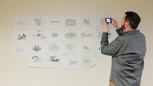 Person photographing branded logo sketches on wall display