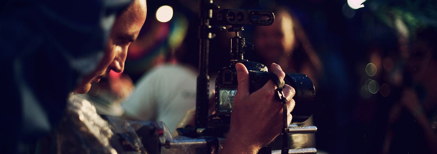 man lookin through camera to film