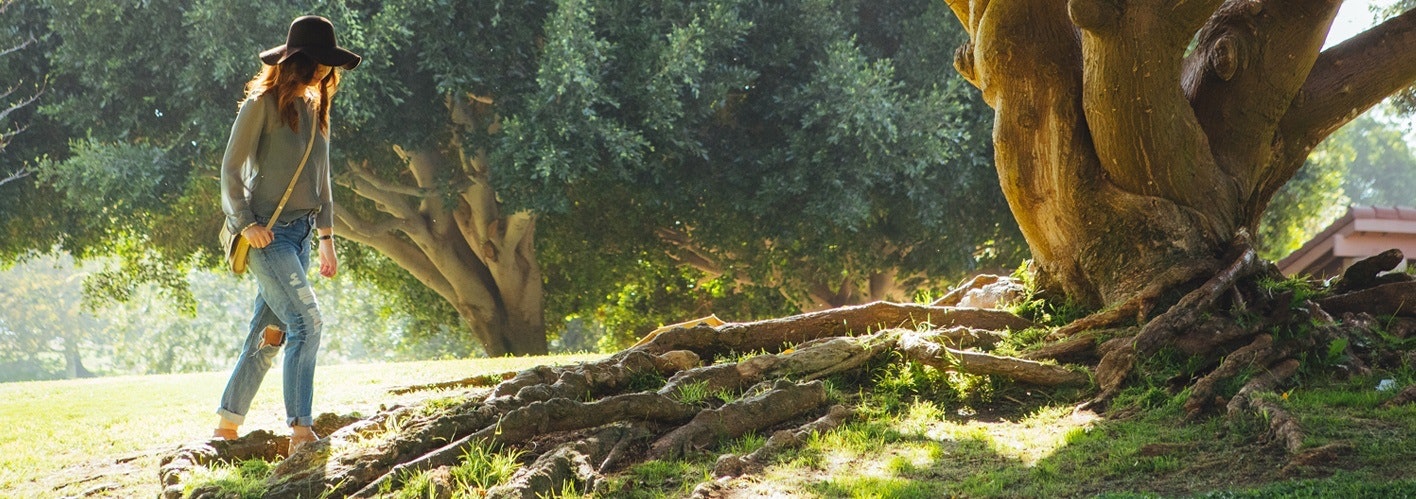 woman walking next to tree with exposed roots