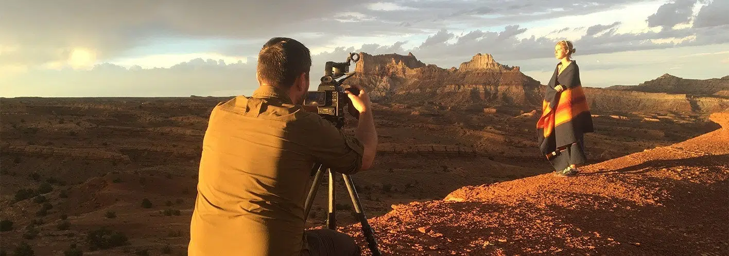 photographer filming a female subject against a beautiful landscape