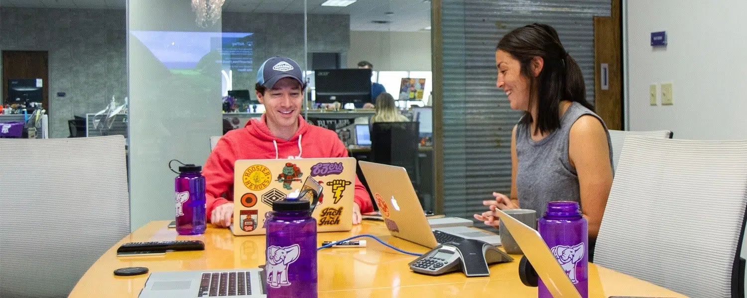 two marketers working on a project around a table while laughing