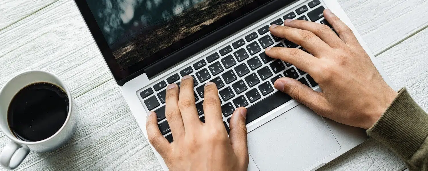 an individual typing at a laptop keyboard