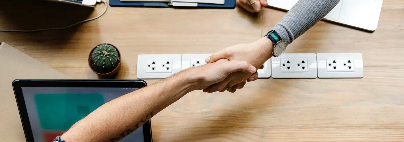 marketer shaking hands with a client across a table