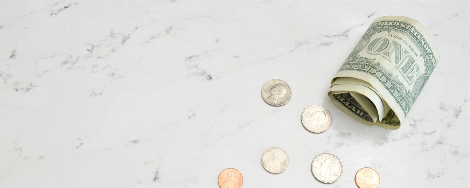 several coins and bills on a marble surface