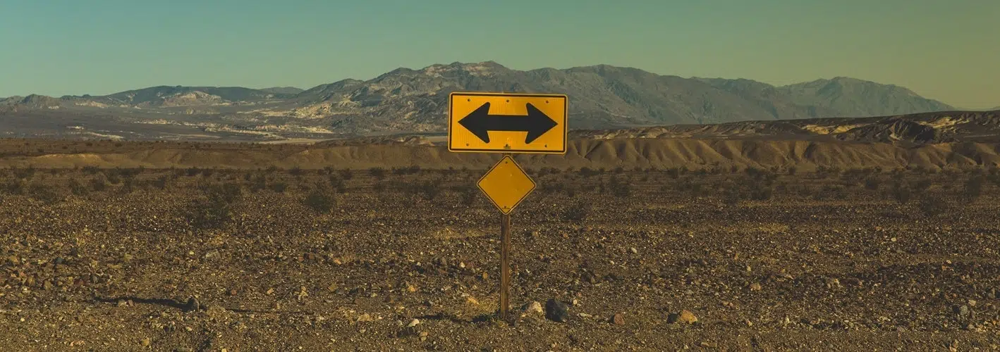 Road sign indicating a T in the road in the middle of a desert