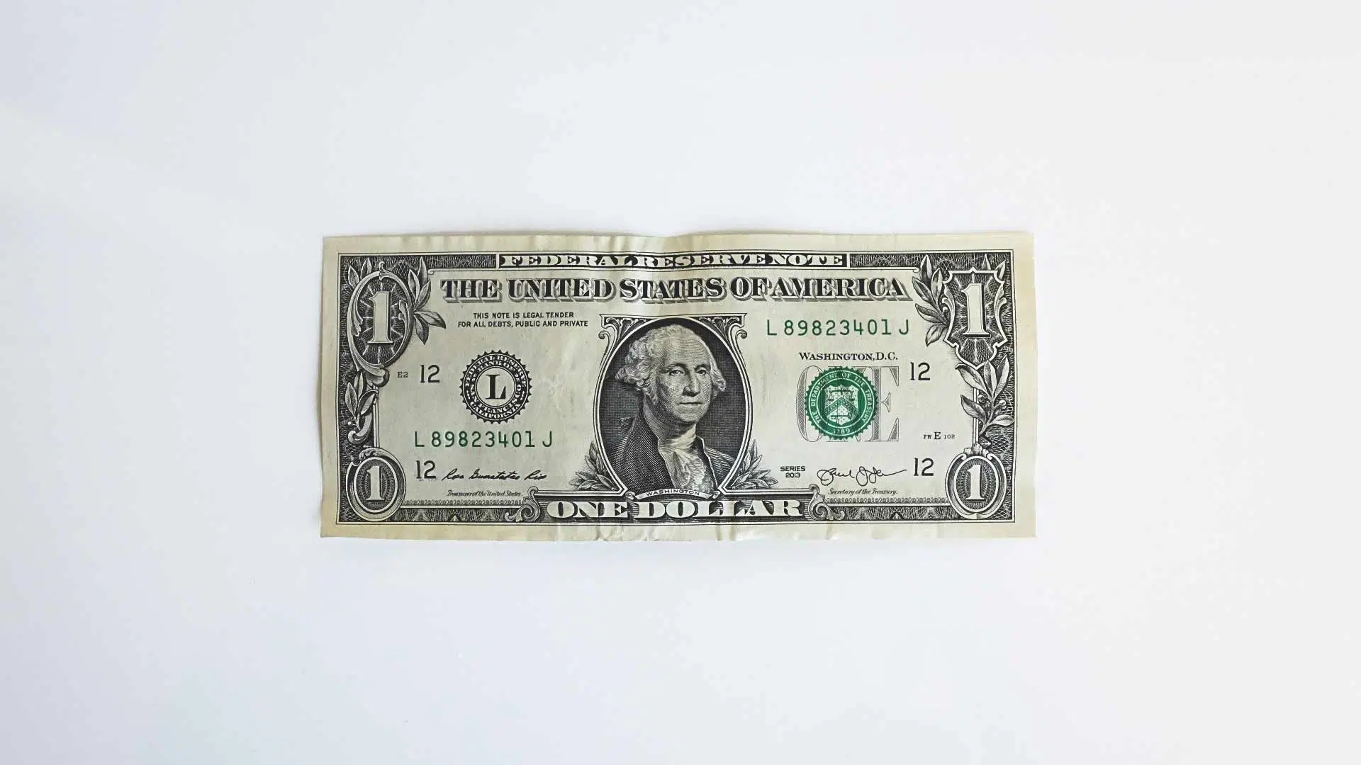 Dollar Bill on White Table in Front of White Bricks