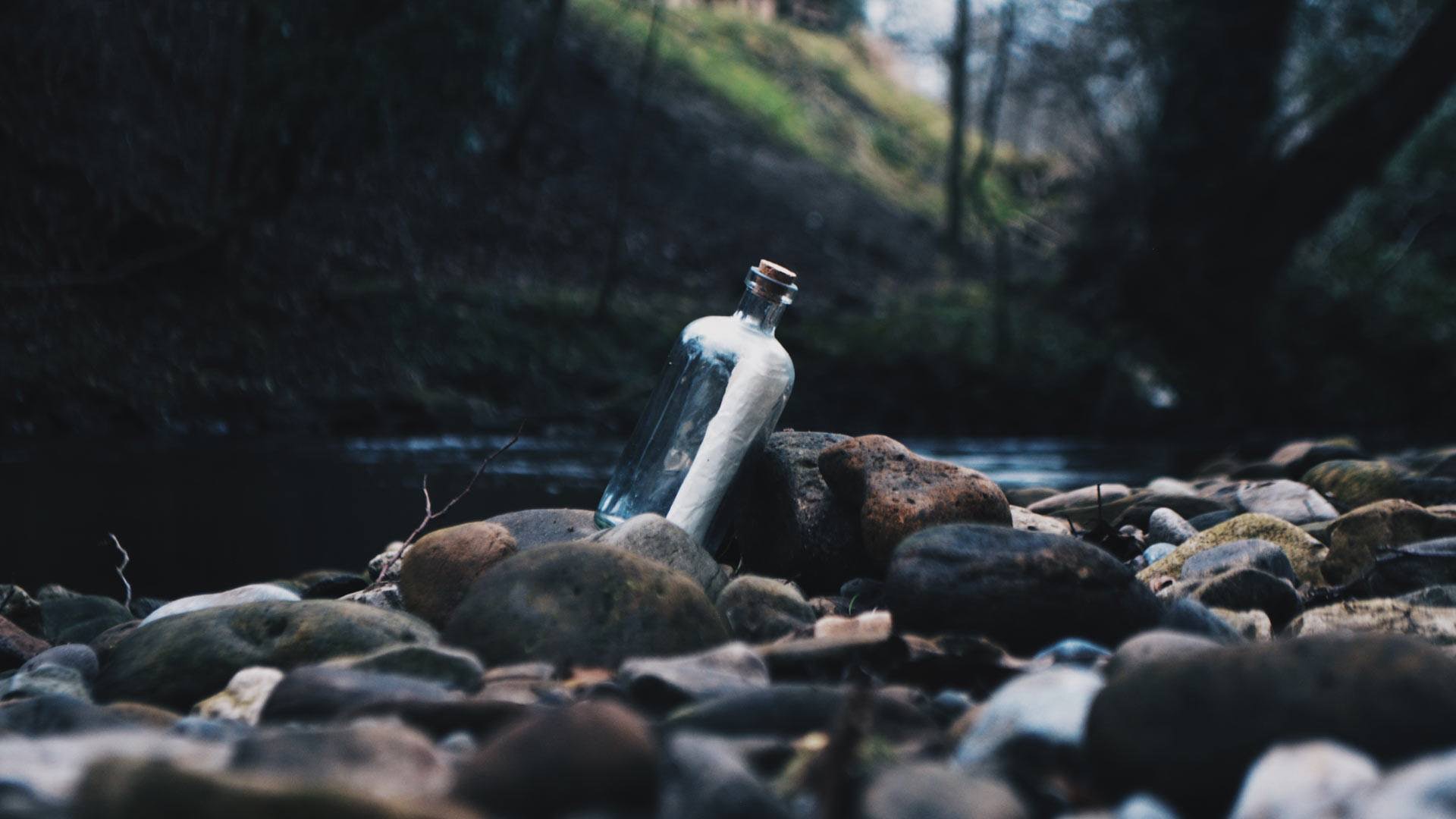 Bottle with Paper inside in the Middle of a Creek