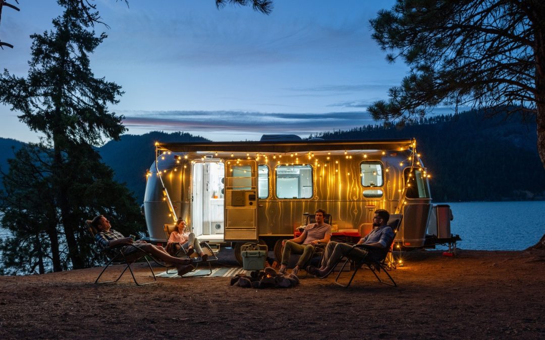 Group of Millennials Camping Outside Airstream in the Pacific Northwest at Twilight