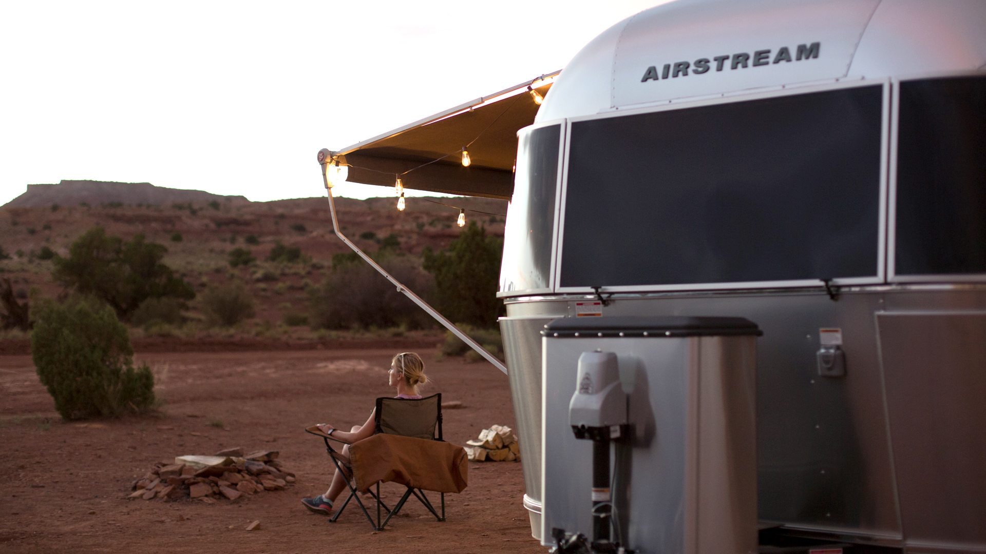 Woman Sitting in Chair Outside Airstream in Desert