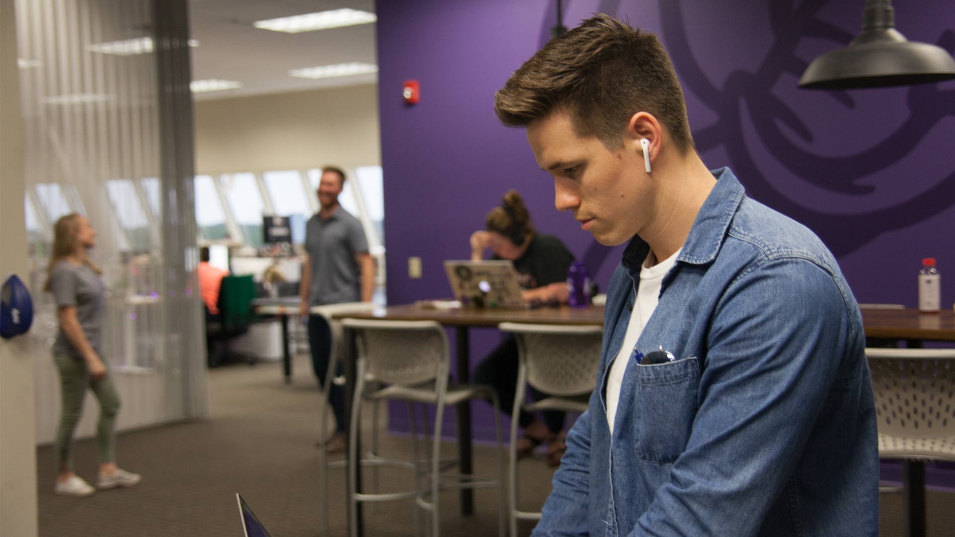 Employee Working in Modern Office with Coworkers in the Background