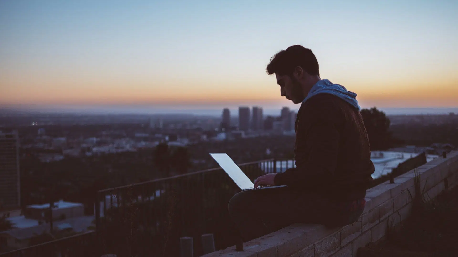 Man on Laptop in Front of Sunset